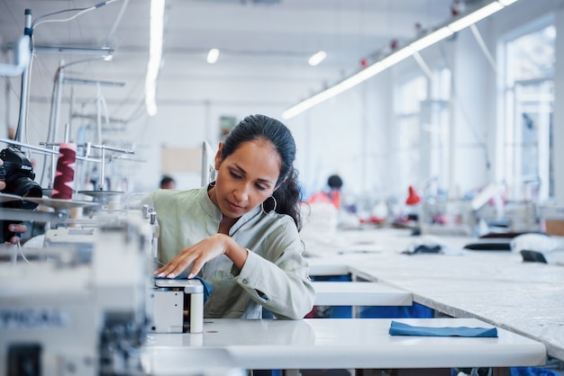 Foto mulher costureira costura roupas na máquina de costura da fábrica.