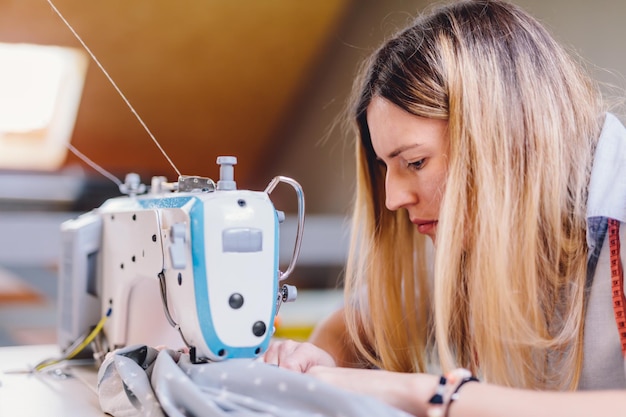 Mulher costureira costureira trabalhando com máquina de costura em sua oficina