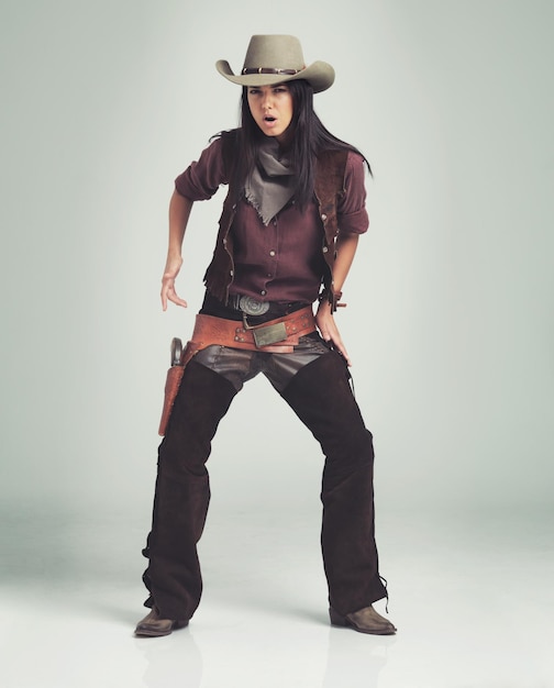 Mulher cowgirl e retrato em estúdio com arma ou traje ocidental em fundo branco revólver ou fora da lei Pessoa feminina selvagem e chapéu com espaço de maquete no Texas para vestir roupa ou acessório