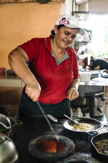 Mulher cozinha em um fogão a lenha