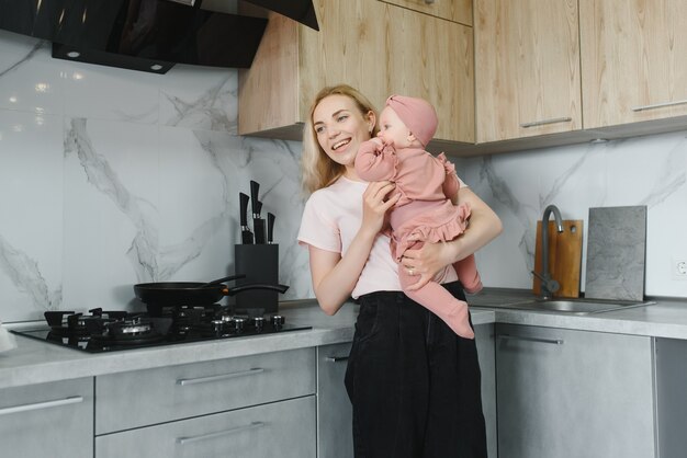 Mulher cozinhando com a filha nas mãos