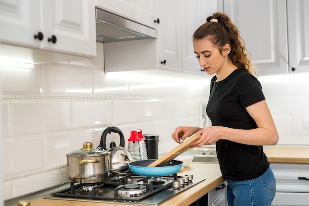 Mulher cozinhando comida na cozinha com frigideira no prato, jantar delicioso fresco. estilo de vida saudável