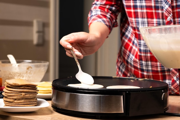 Foto mulher cozinhando crepe delicioso em fabricante de panquecas elétrica em close-up da cozinha