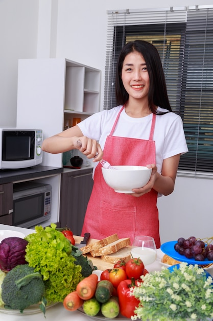 Mulher cozinhando e mexendo ovos em uma tigela na cozinha