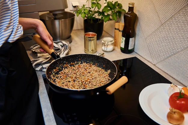 Mulher cozinhando molho à bolonhesa na cozinha