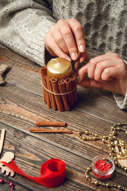 Mulher criando presentes de Natal elegantes e decorando velas com canela