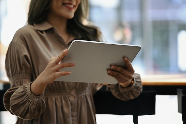 Mulher criativa em pé no escritório e usando tablet digital