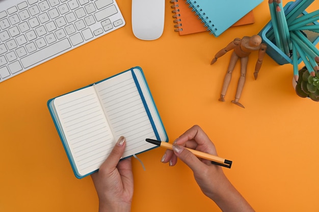 Mulher criativa segurando caneta e fiação no caderno vazio
