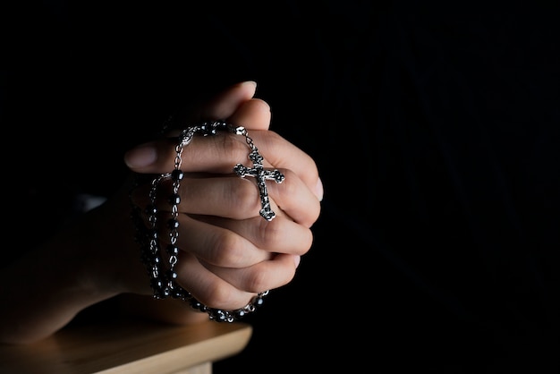 Mulher cristã ora por bênçãos com fé em um fundo preto