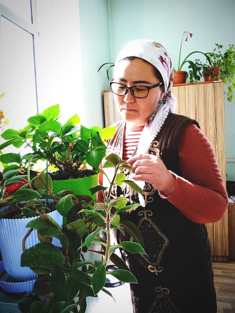 Foto mulher cuidando de plantas em vaso em casa