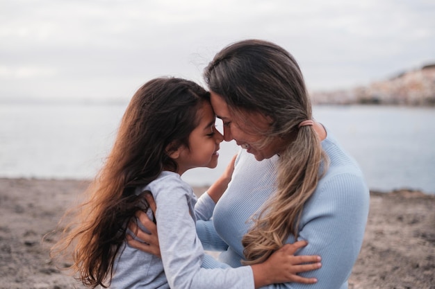 Mulher cuidando de sua filha ao ar livre e à beira-mar e mostrando seu amor Conceito maternidade crescimento infantil