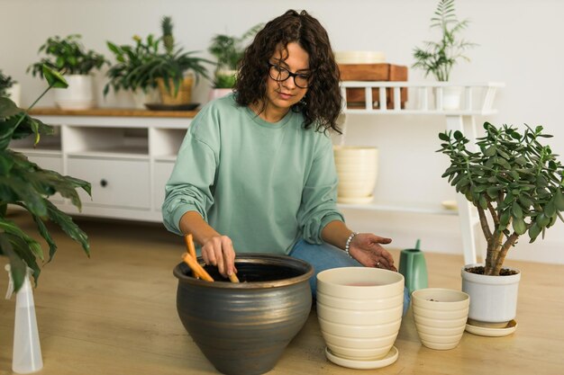 Foto mulher cultiva vasos de plantas em casa, rega e cuida de flores, jardinagem e cuidados com plantas domésticas