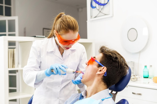 Mulher curando os dentes do paciente na clínica