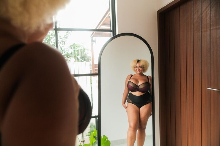 Foto mulher curva afro-americana de tamanho maior de pé no espelho olhando para o reflexo