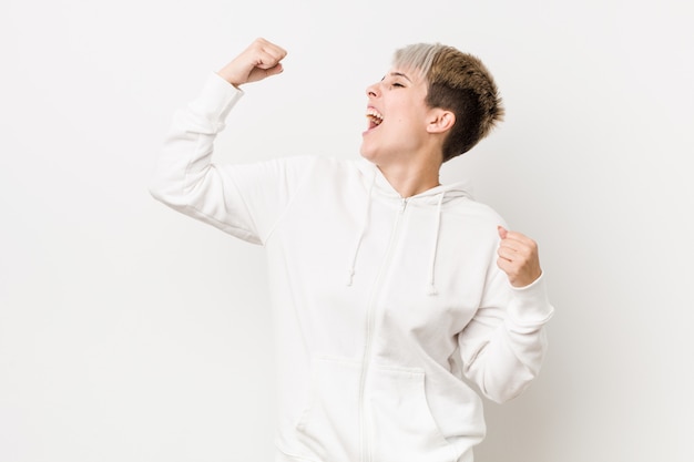 Mulher curvy nova que veste um hoodie branco que aumenta o punho após uma vitória, conceito do vencedor.