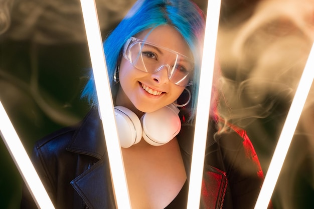 Mulher cyberpunk Estilo scifi Subcultura futurista Modelo sorridente feliz atraente em fones de ouvido em luz de neon de lâmpada LED em fundo de fumaça escura