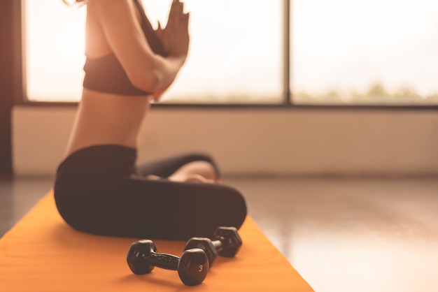 Mulher da beleza da vista lateral que faz a ioga e levanta a mão ou paga a reverência no trai dos exercícios da aptidão