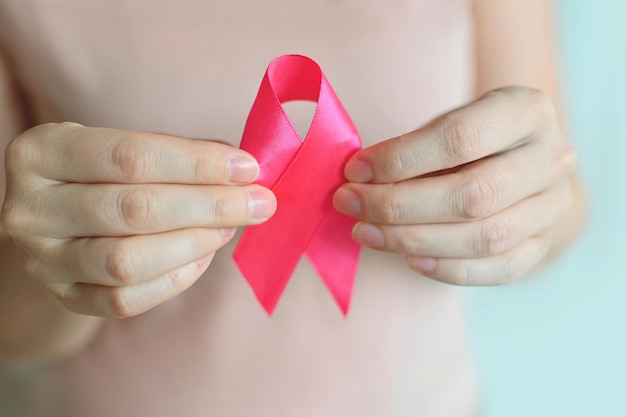 Mulher da conscientização do câncer de mama em uma camiseta rosa com a mão segurando a fita rosa dia mundial do câncer