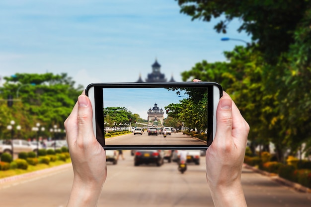 Mulher da mão que toma a foto na vitória Puerta Patuxai, Vientiane, Laos, Sudeste Asiático.