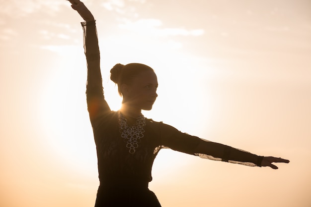 Mulher dançando ao nascer do sol