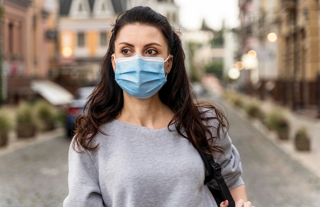 Foto mulher dando um passeio na cidade usando uma máscara médica