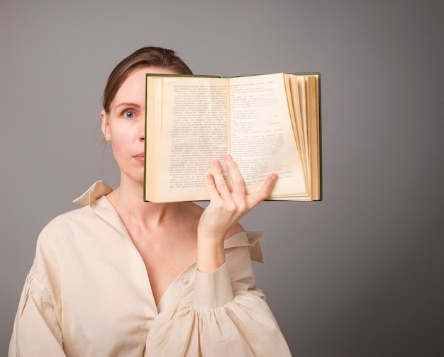 Mulher de 40 anos com um livro sobre um fundo claro