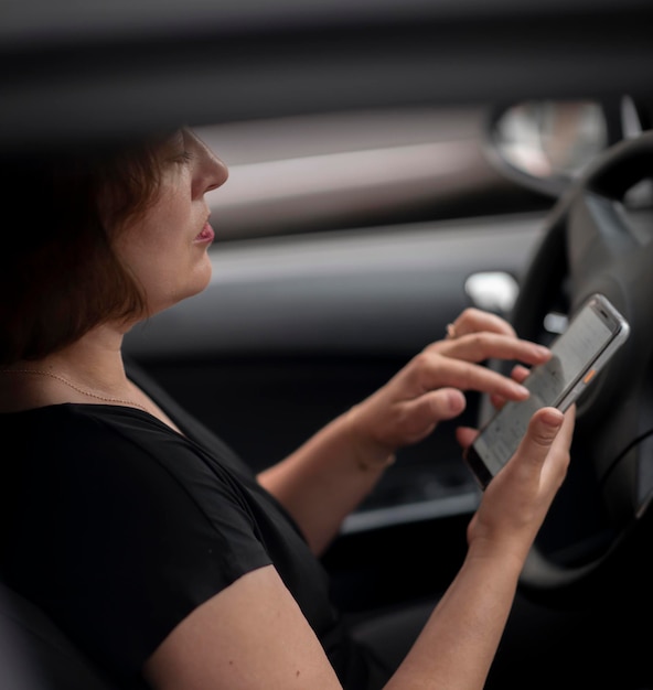Mulher de 48 anos em um carro olhando para o telefone enquanto dirige