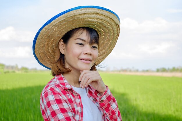 Mulher de agricultor asiático retrato posa pensando na fazenda de arroz verde.