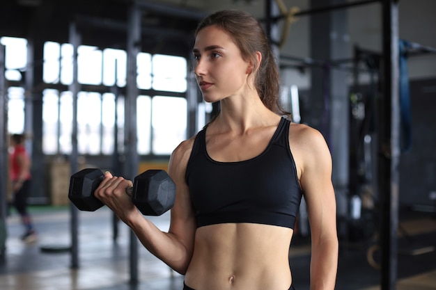 Mulher de ajuste muscular exercitando músculos de construção no ginásio.