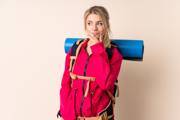 Mulher de alpinista com uma mochila grande sobre isolado pensando uma idéia