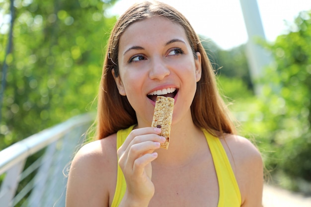 Mulher de aptidão comendo uma barra de energia.