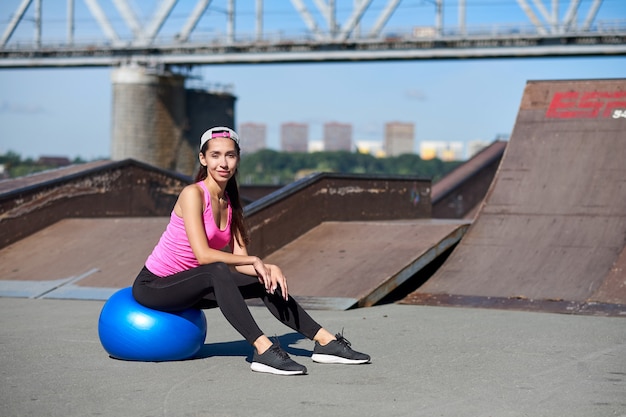 Mulher de aptidão fazendo exercícios de alongamento com ajuste bola na cidade urbana