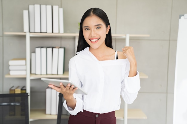 Mulher de ásia com tablet comemorando o conceito de sucesso