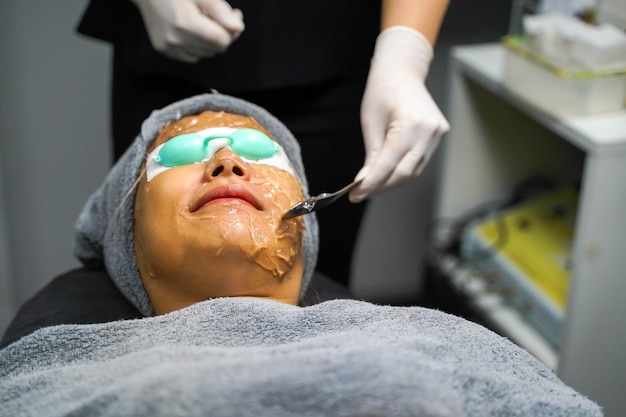 Mulher de beleza asiática fechada recebendo gel de pele para preparar a terapia de luz colorida