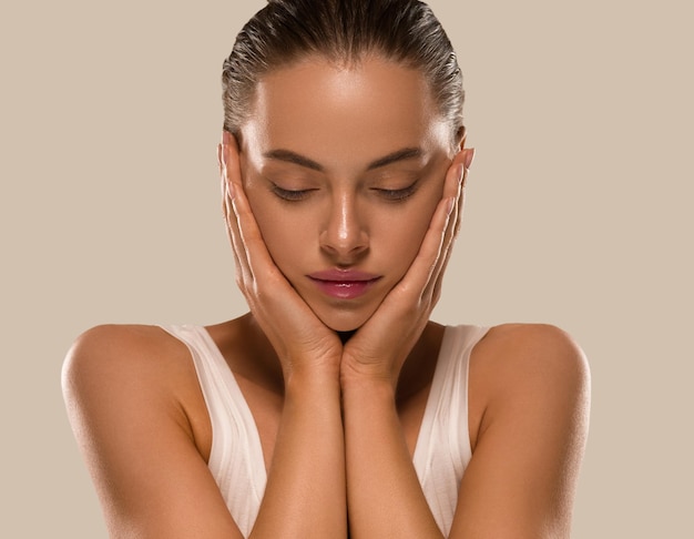 Mulher de beleza com mãos saudáveis, maquiagem natural limpa, conceito de pele fresca, cor de fundo marrom