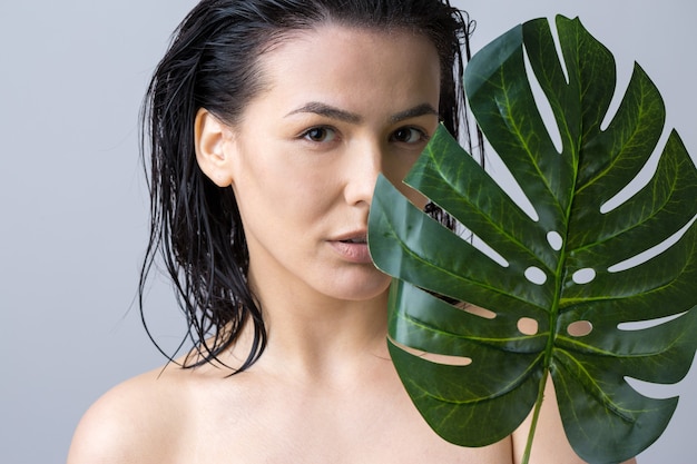 Mulher de beleza com retrato em folha de palmeira verde natural. Moda, beleza, maquiagem, cosméticos.