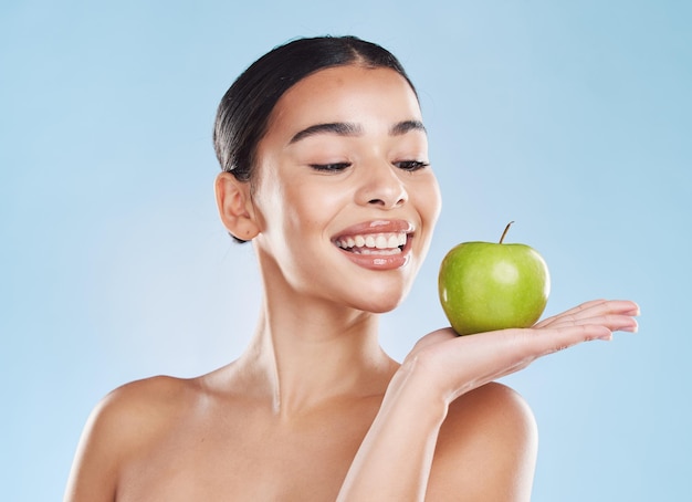 Mulher de beleza de cuidados com a pele com maçã na mão com saúde cosmética de bem-estar e dentes dentários em estúdio Retrato de dieta saudável de pele modelo de menina com sorriso e produto de frutas