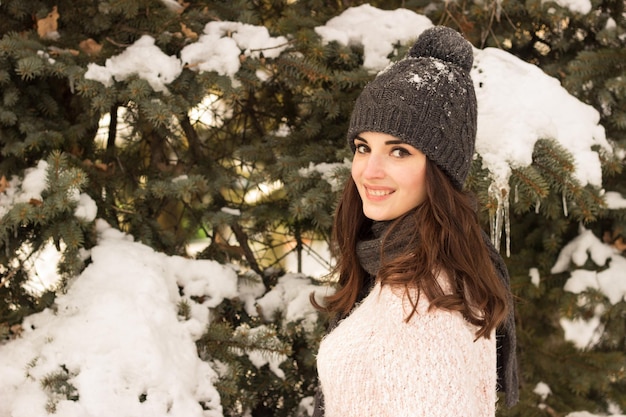 Mulher de beleza no parque com chapéu quente com árvore atrás