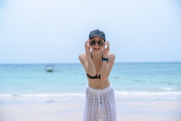 Mulher de biquíni preto na praia tropical. Mulher de retrato em trajes de banho desfrutando e postando na praia.