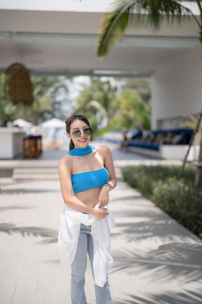 Mulher de blusa azul e jeans andando no hotel resort tropical