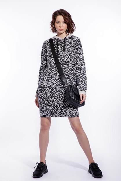 Mulher de blusa cinza com estampa de leopardo saia bolsa de tênis preto no estilo de caminhada de fundo branco