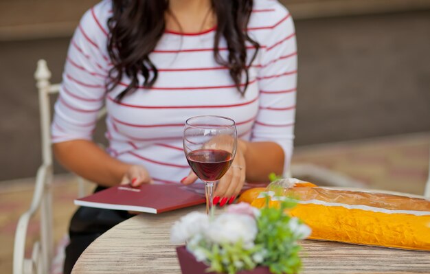 Mulher de boné vermelho bebendo vinho tinto no café ao ar livre