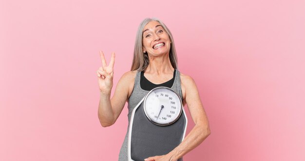 Foto mulher de cabelo branco de meia-idade segurando um conceito de dieta e fitness de escala de peso