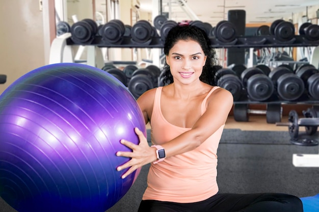 Mulher de cabelo encaracolado segura uma bola no centro de fitness