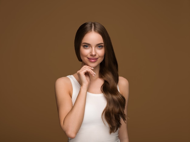 Mulher de cabelo longa e saudável com retrato de rosto de pele de beleza de cabelo longo encaracolado. Cor de fundo marrom