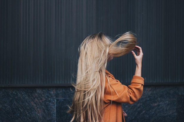Mulher de cabelo longo de pé contra a parede