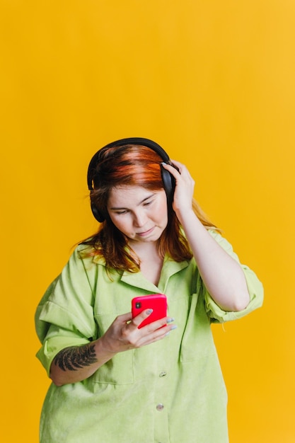 Mulher de cabelo vermelho ouvindo música em seu telefone através de fones de ouvido