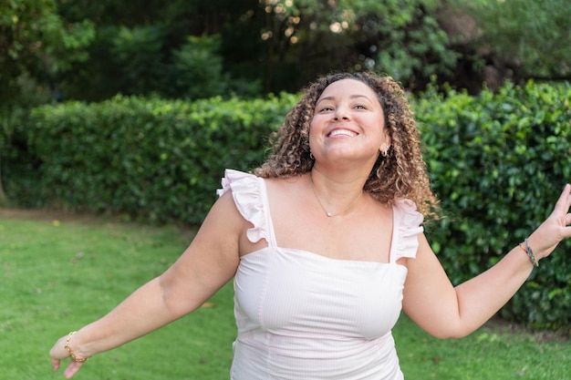 Mulher de cabelos cacheados feliz e sorrindo com olhar de esperança