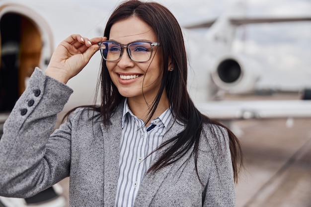 Foto mulher de cabelos escuros bonita caucasiana feliz está embarcando em um jato particular