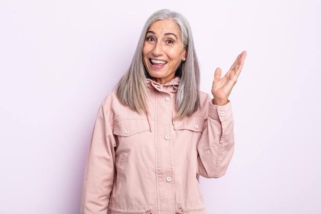 Mulher de cabelos grisalhos de meia-idade se sentindo feliz, surpresa e alegre, sorrindo com atitude positiva, percebendo uma solução ou ideia